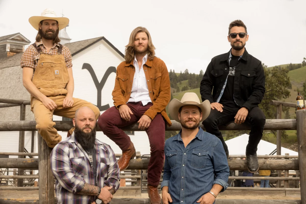 An image of the band members from Shane Smith & The Saints in front of the television show, "Yellowstone's" prop barn