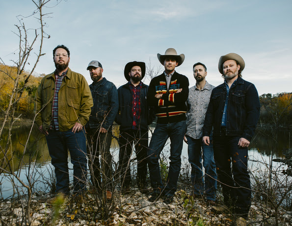 A promo image of the band members of Turnpike Troubadours, standing in front of a lake or river
