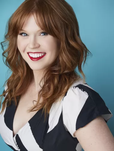 An image of author, Erin La Rosa, standing in front of a bluish-tinted background, smiling