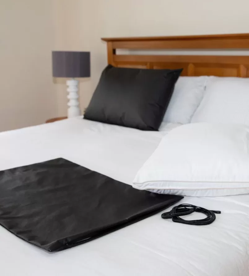 An image of the Earthing Grounding Pillow Cover with a full bed and lamp in background